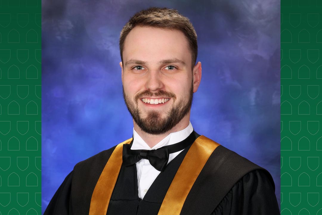 Head and shoulders portrait of Brad Heskin in a black graduation robe. 